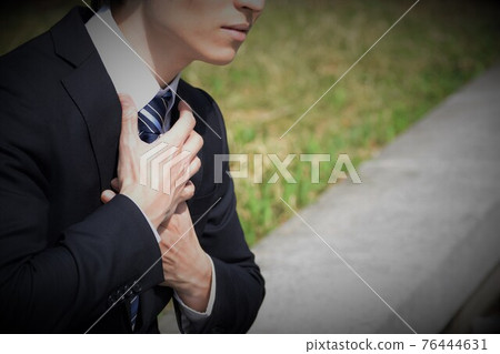 A man in a suit with his hands on his chest 76444631