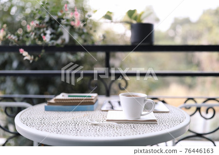 White coffee cup and notebooks on vintage metal table at balcony White coffee cup and notebooks on vintage metal table at balcony 76446163