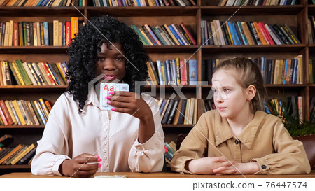 Individual tutor teaches schoolgirl letters with flashcards 76447574