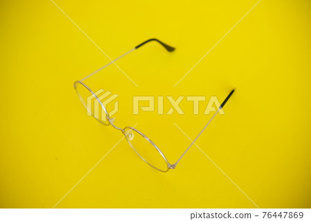 Silver metal glasses. On a solid yellow background. With a soft blurred electoral background. Eyepieces, Vision 76447869