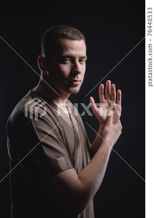 Studio portrait of a young Caucasian massage therapist with an athletic physique. Stretches his hands looking at the camera Studio portrait of a young Caucasian massage therapist with an athletic physique. Stretches his hands looking at the camera 76448533