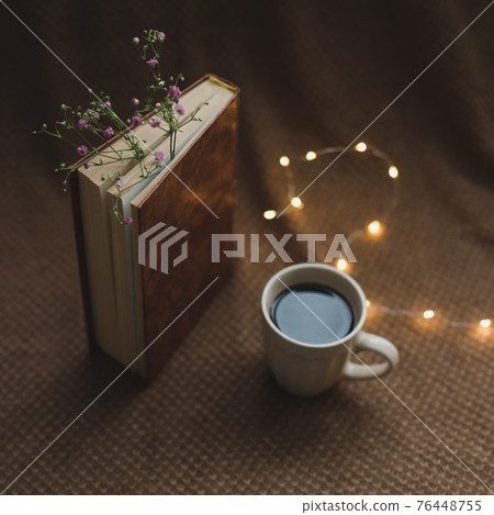 A book with flowers and cup of coffee on dark background top view A book with flowers and cup of coffee on dark background top view 76448755