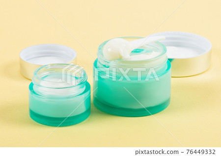 White cream in a blue jar on a yellow background. Cosmetic product for skin care. White cream in a blue jar on a yellow background. Cosmetic product for skin care. 76449332