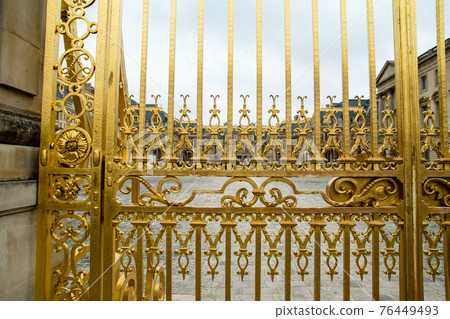 The golden gate fence of the Palace of Versailles in Paris, France and the palace in the distance The golden gate fence of the Palace of Versailles in Paris, France and the palace in the distance 76449493