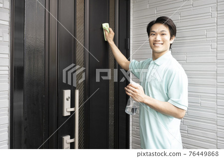 House cleaning male worker wiping the front door 76449868