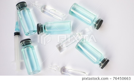 Vial vaccine, top view of glass ampoules with transparent and blue liquid lying on white background, global vaccination concept Vial vaccine, top view of glass ampoules with transparent and blue liquid lying on white background, global vaccination concept 76450663