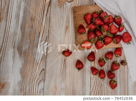 Juicy red strawberry lies on the wooden board Juicy red strawberry lies on the wooden board 76452036