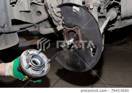 Auto mechanic hands holding the wheel hub. Close-up. Replacement of spare parts in a car service. Auto mechanic hands holding the wheel hub. Close-up. Replacement of spare parts in a car service. 76453680