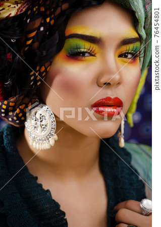 beauty bright woman with creative make up, many shawls on head like cubian, ethno look closeup 76454801