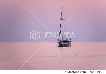 Sailing yacht in the blue sea during beautiful pink sunset. 76454943