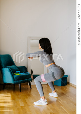 Attractive fitness woman doing squat workout at home 76454984