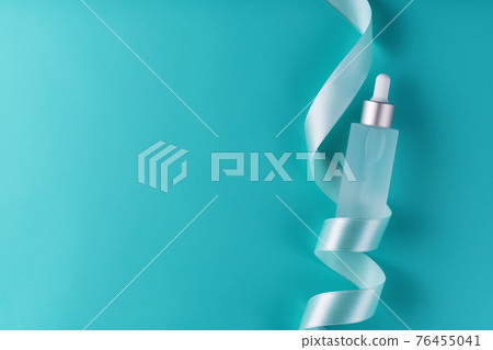 Natural cosmetics, serum for hair and skin care and mint ribbon on a blue background, top view. Natural cosmetics, serum for hair and skin care and mint ribbon on a blue background, top view. 76455041