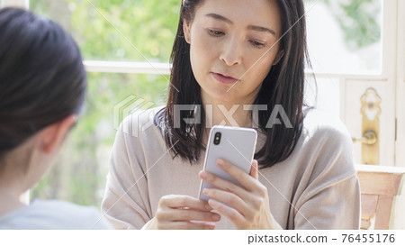 Two women looking at a smartphone together 76455176