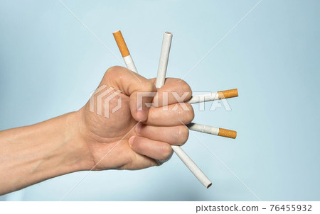 Hand holding many cigarettes and blue background. Stop smoking, World No Tobacco Day on May 31 concept. Selective focus 76455932