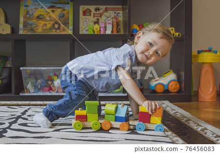 Happy cute child having fun playing with colorful wooden train, at home. 76456083