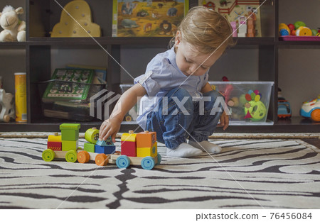 Happy cute child having fun playing with colorful wooden train, at home. 76456084