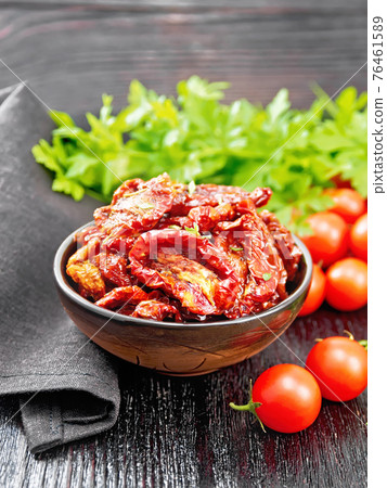 Tomatoes sun-dried in bowl with napkin on dark board Tomatoes sun-dried in bowl with napkin on dark board 76461589