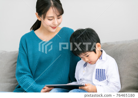 坐在沙發上，看到平板電腦的親子 76465180