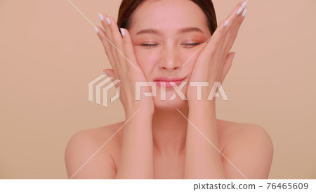 A young woman massaging her face. 76465609