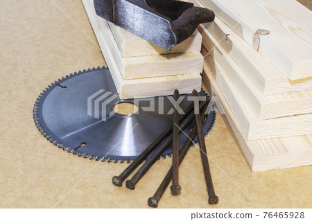 Wooden pine boards . Space for the text. A saw and an old plane. Wooden pine boards . Space for the text. A saw and an old plane. 76465928