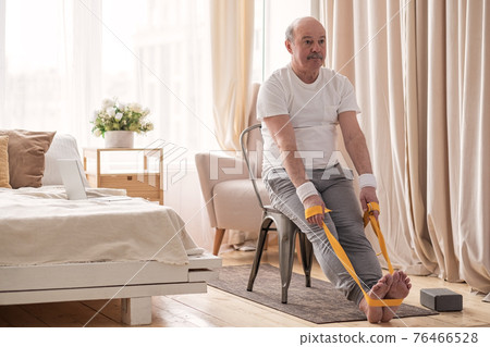 Man sitting on chair doing paschimottanasana or Intense Dorsal Stretch pose 76466528