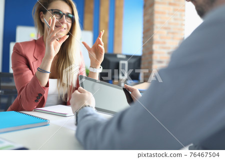 Businesswoman communicates at her desk with colleague Businesswoman communicates at her desk with colleague 76467504