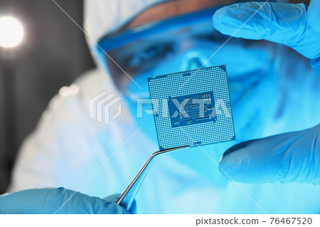 Scientist developer in protective suit holds microcircuit 76467520