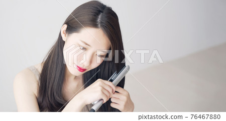 Women styling with curling irons 76467880