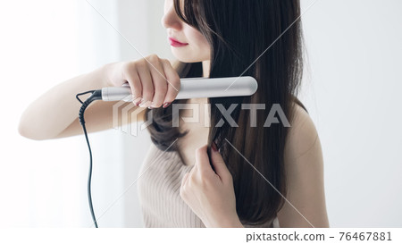 Women styling with curling irons 76467881
