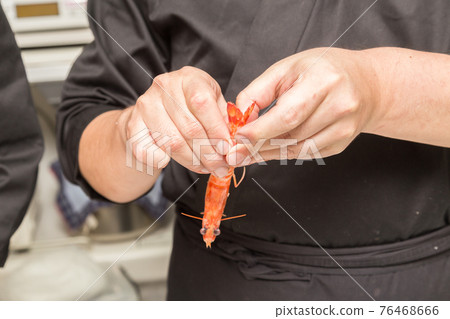 Hands in front of the board to peel the prawns 76468666