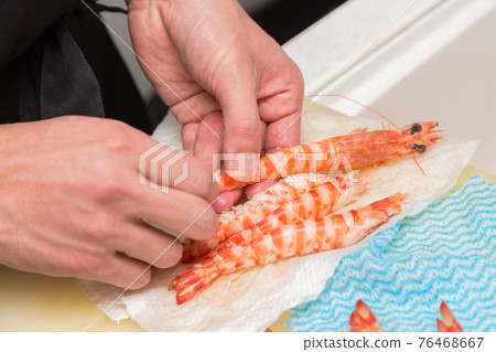 Hands in front of the board to peel the prawns 76468667