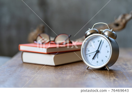 放在邊桌上的鬧鐘、眼鏡、書和被冉冉升起的太陽照亮的枯樹 放在邊桌上的鬧鐘、眼鏡、書和被冉冉升起的太陽照亮的枯樹 76469643