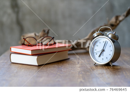 放在邊桌上的鬧鐘、眼鏡、書和被冉冉升起的太陽照亮的枯樹 放在邊桌上的鬧鐘、眼鏡、書和被冉冉升起的太陽照亮的枯樹 76469645