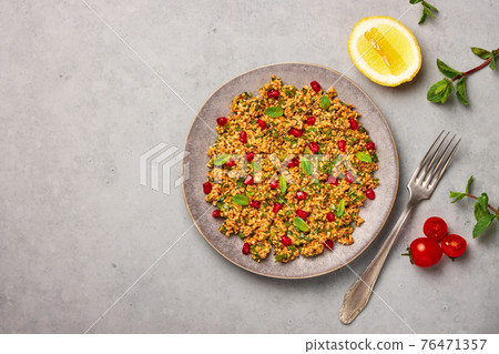 Kisir on gray plate on concrete table top. Turkish cuisine bulgur and parsley salad dish Kisir on gray plate on concrete table top. Turkish cuisine bulgur and parsley salad dish 76471357
