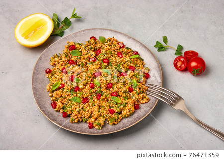 Kisir on gray plate on concrete table top. Turkish cuisine bulgur and parsley salad dish Kisir on gray plate on concrete table top. Turkish cuisine bulgur and parsley salad dish 76471359