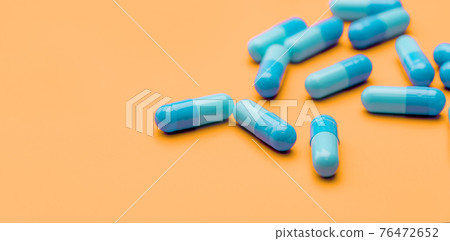 Blue antibiotic capsule pills spread on yellow background. Antibiotic drug resistance. Pharmaceutical industry. Healthcare and medicine concept. Health budget concept. Capsule manufacturing industry. 76472652