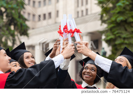 Happy multiracial group of students raising diplomas Happy multiracial group of students raising diplomas 76475124