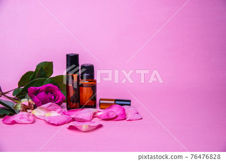 Bottles with essential rose oil or organic serum over pink background 76476828