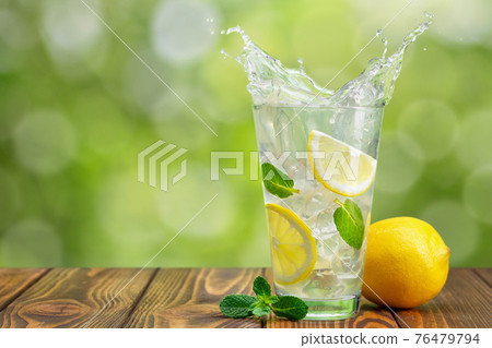 lemonade in glass on wooden table with green blurred background 76479794