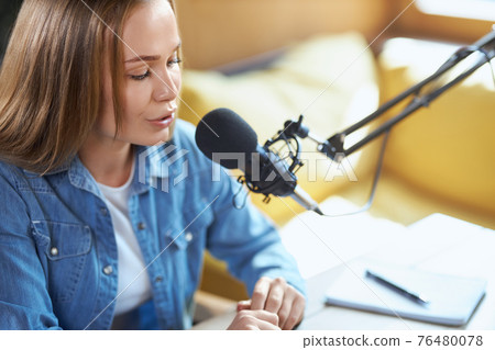 Young woman telling facts or news in microphone on radio.  76480078