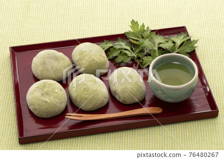 紅盤上排列著艾草葉的草麻糬 紅盤上排列著艾草葉的草麻糬 76480267