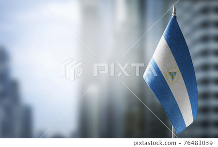 A small flag of Nicaragua on the background of a blurred background 76481039
