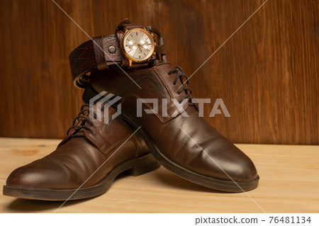 Men's accessories with brown leather belt, shoes and watch on wooden background Men's accessories with brown leather belt, shoes and watch on wooden background 76481134