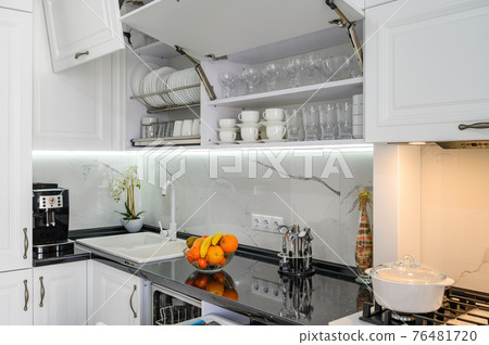 Luxurious white modern kitchen interior, drawers pulled out, doors open 76481720