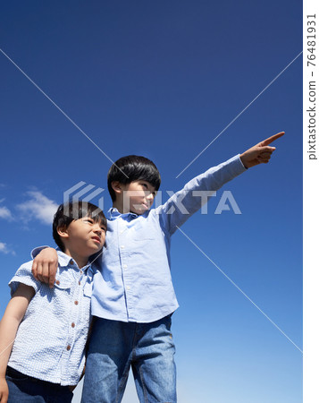 A boy pointing his finger at the blue sky 76481931