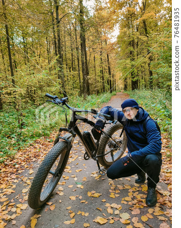 Sporty man on an electric bike in the woods. A pleasant sports hobby. Ecological transport. Sporty man on an electric bike in the woods. A pleasant sports hobby. Ecological transport. 76481935