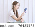 Beautiful woman use phone and smile on white background 76483378