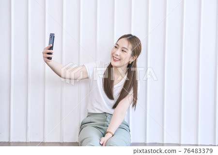 Closeup portrait of Asian lady smile and taking selfie at her home. Concept woman lifestyle Closeup portrait of Asian lady smile and taking selfie at her home. Concept woman lifestyle 76483379