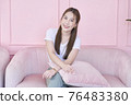 Happy woman smile and sitting on pink sofa at home 76483380