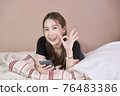 Good looking cute woman shows great sign or OK sign and hold phone 76483386